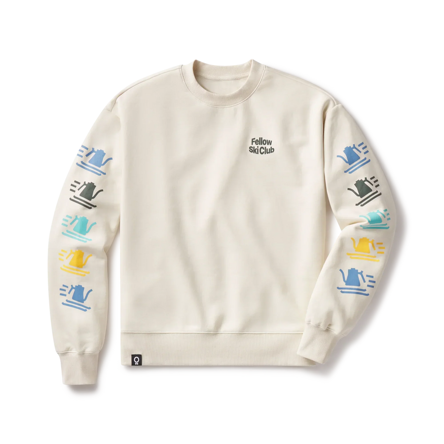 The beige Fellow Ski Club Crewneck by Fellow displays Fellow Ski Club on the chest and vibrant abstract designs in blue, yellow, black, and green on both sleeves. - media