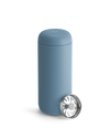 A Fellow Carter Move Mug in blue sits beside its metal strainer on a white background.