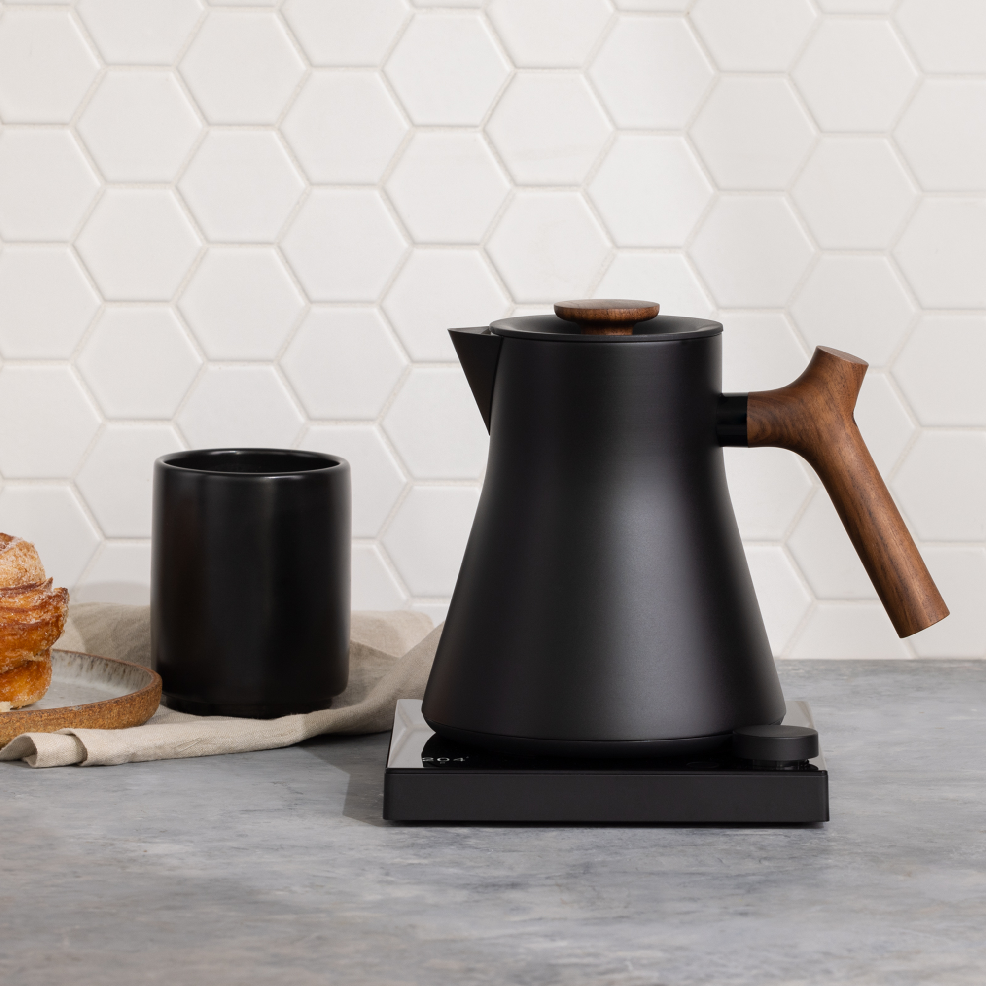 Sleek black electric kettle with wooden handle for the perfect home barista coffee setup.