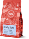 Red Olympia Holiday Blend coffee bag with white winter illustrations and label details.