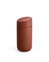 A matte rust-red Carter Slide Mug by Fellow with a rounded lid on a white background.