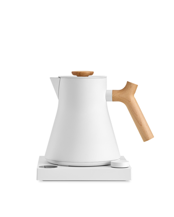 Fellow Corvo EKG Electric Kettle with wooden handle on a sleek white base.