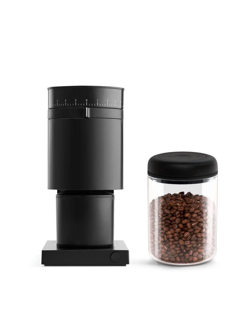 Fellow The Grind It Kit with coffee grinder and beans in a glass jar on white background.