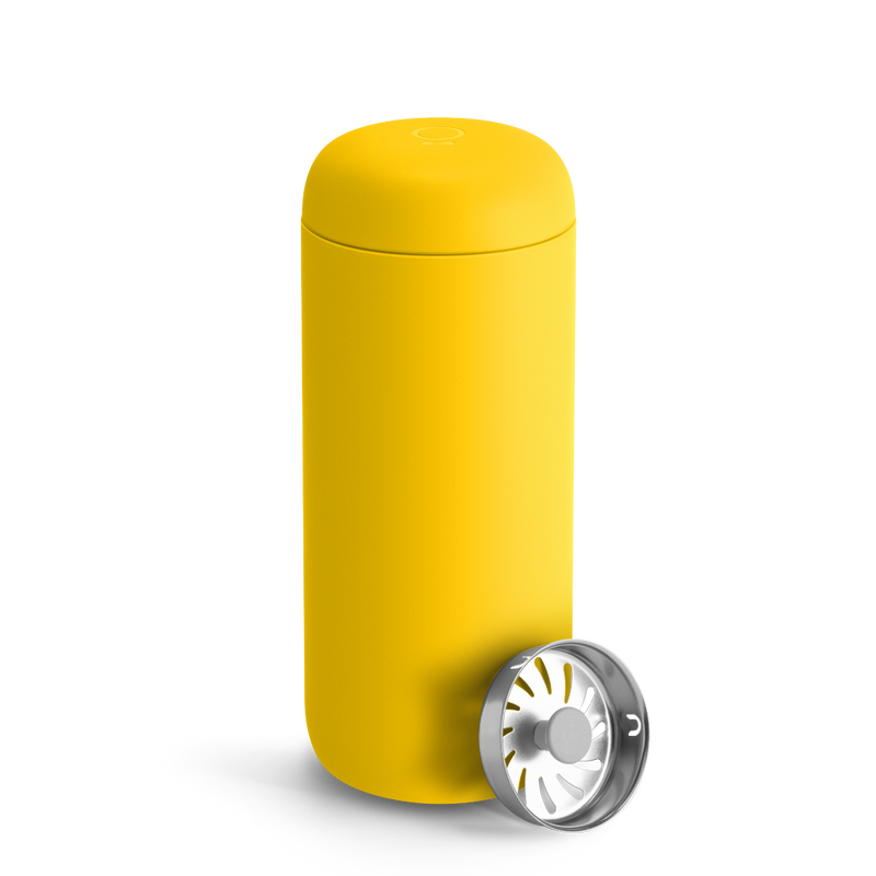 Fellow Carter Move Mug in Lemon Zest with rounded edges and a metal strainer in front.